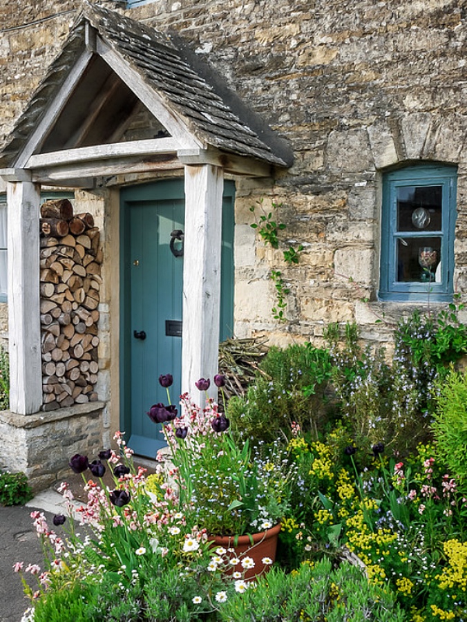 Flowers by the front door of an old stone cottage with blue door