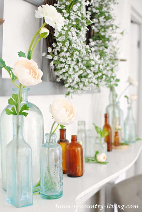 Summer mantel with vintage bottles and white flower wreath