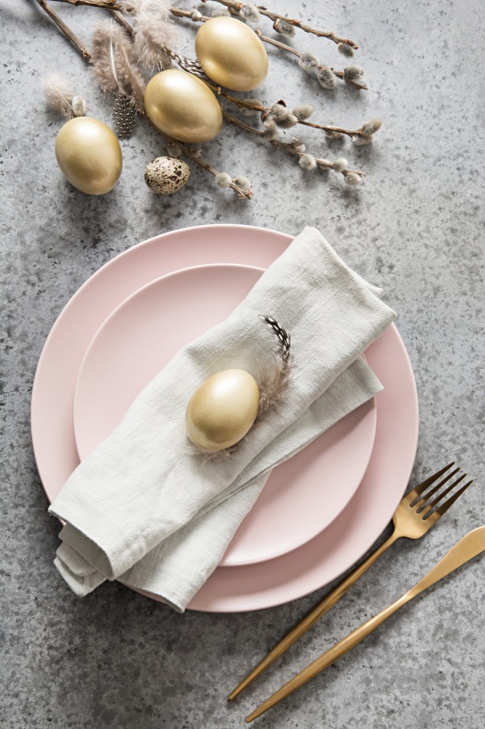 Easter table setting with pink plate and golden eggs on grey stone table