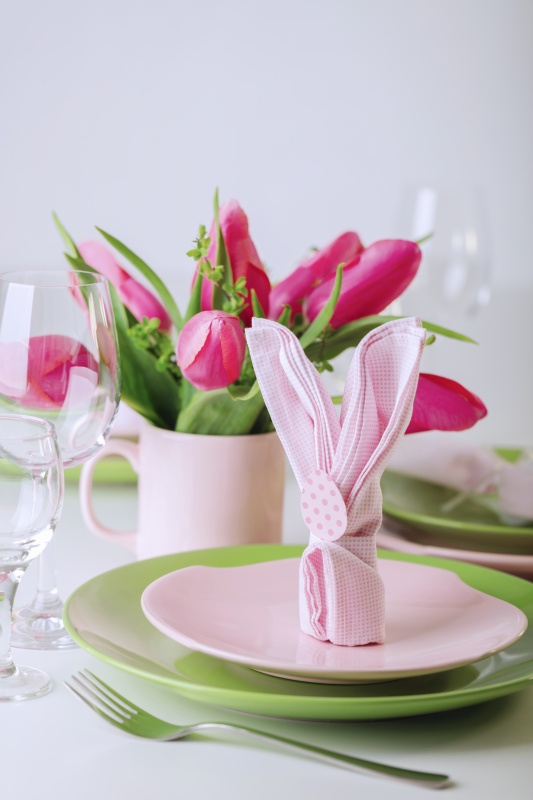 Happy easter. Decor and table setting of the Easter table is a vase with pink tulips and dishes of pink and green color. 