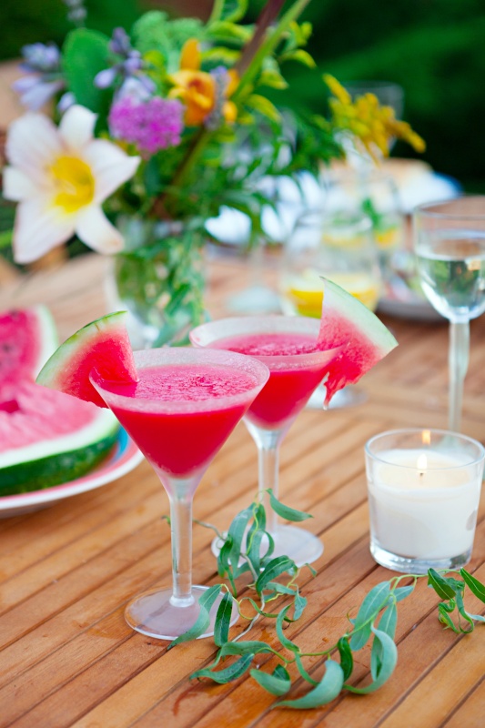 Two glasses of watermelon cocktail. Family outdoor dinner in garden in summertime at sunset. 