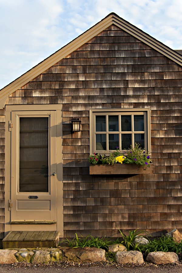 Simple craftsman style cottage with wood shingles and flower-filled window box.