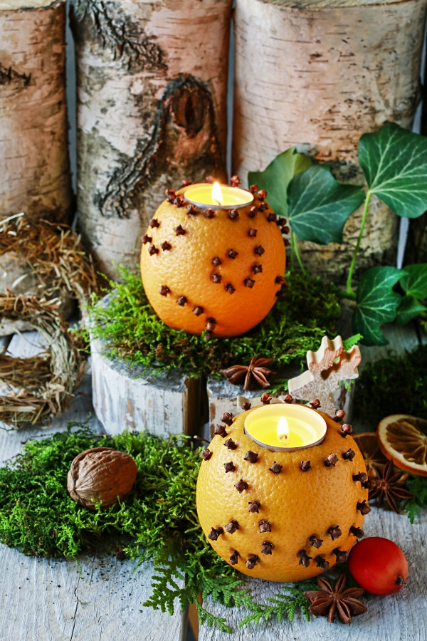 Christmas home decoration with pomander, candles, moss and paradise apples. 