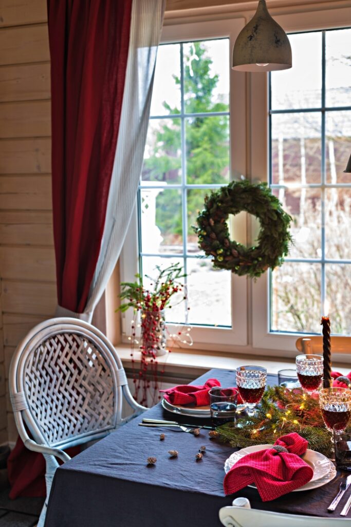 Table served for Christmas dinner, festive setting with decorations, burning candles and fir-tree branches, glasses
