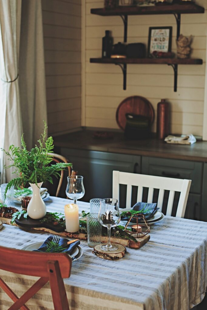 rustic country kitchen interior with festive table setting for summer dinner in natural green and brown tones. 