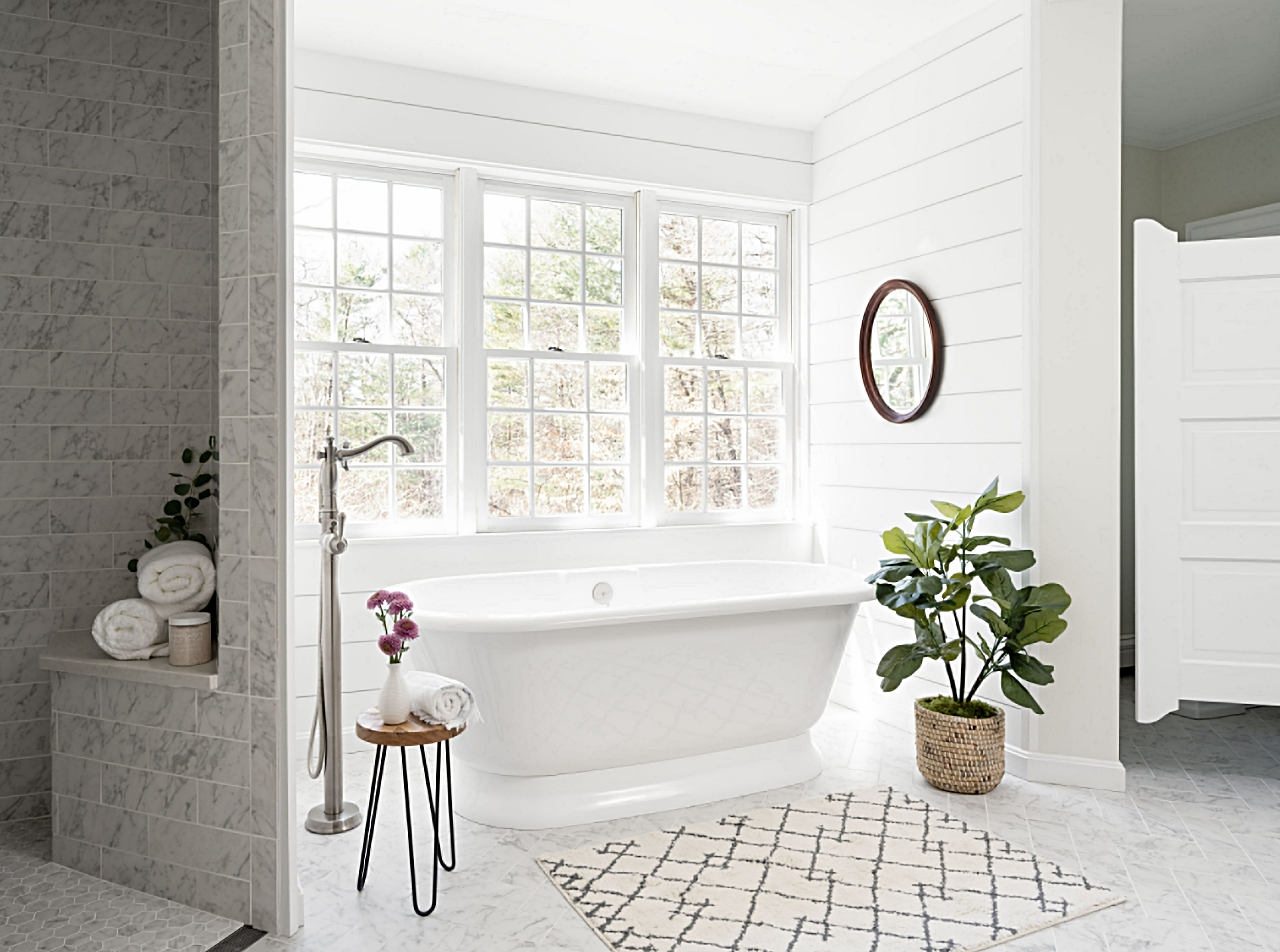 white bathroom with freestanding tub under window