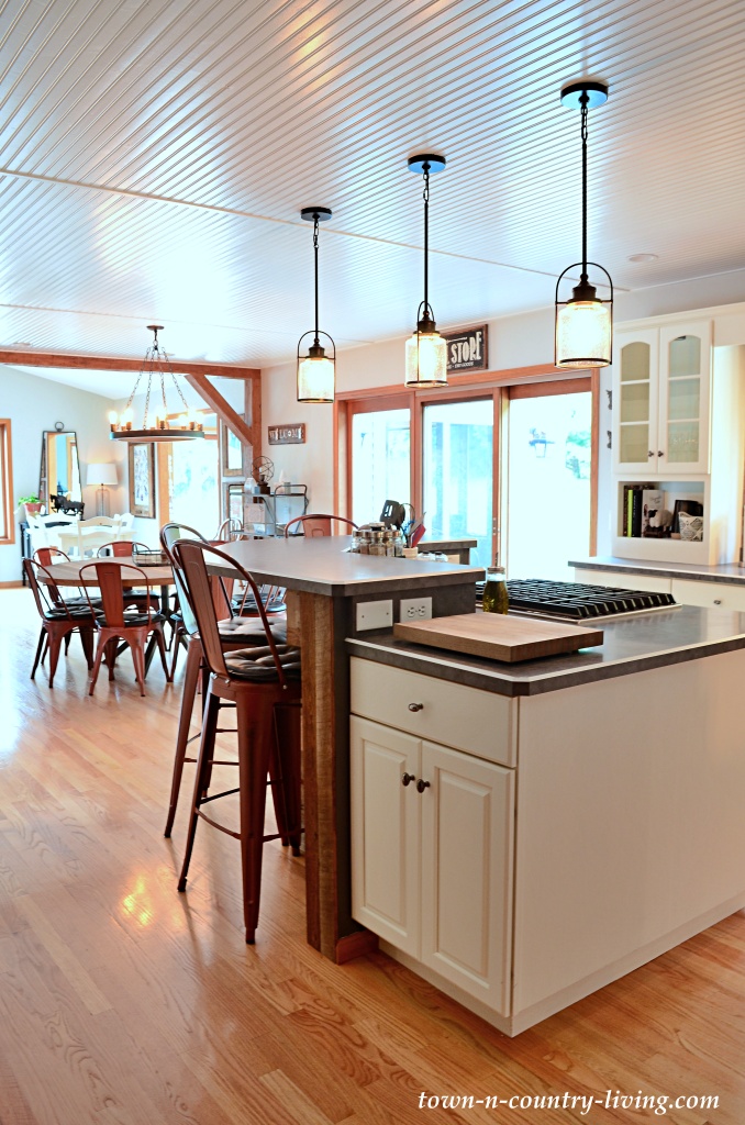 Large kitchen island with cooktop and red barstools in a farmhouse style kitchen