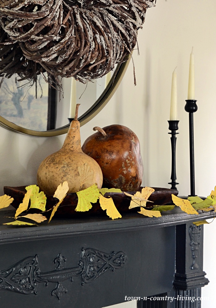 Decorate for fall by adding gourds and a leaf garland to a vintage mantel