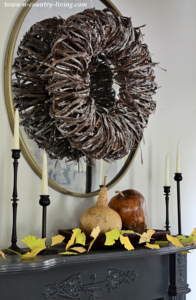 Decorate for fall by adding gourds and a leaf garland to a vintage mantel