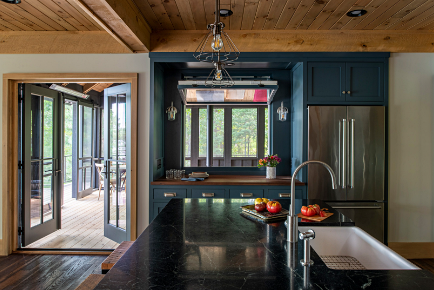 Lakefront cabin kitchen with dark blue cabinets and wood ceiling