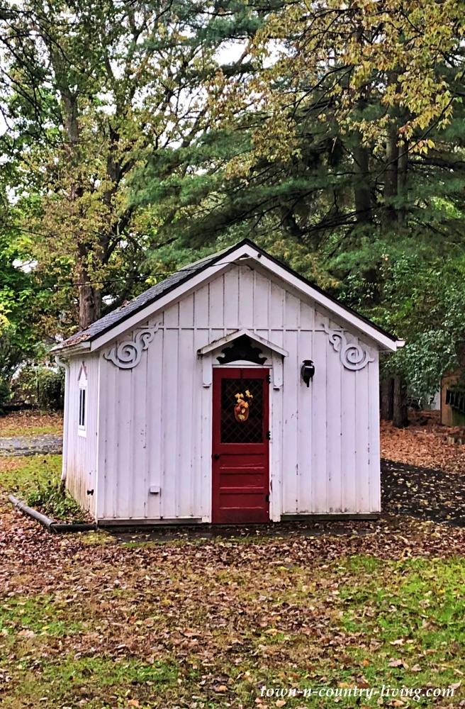 Small white garden shed with red door