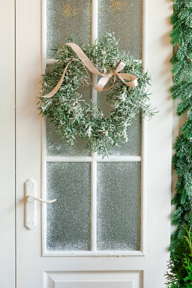 Beautiful stylish Christmas wreath with a satin bow on the white door of the house