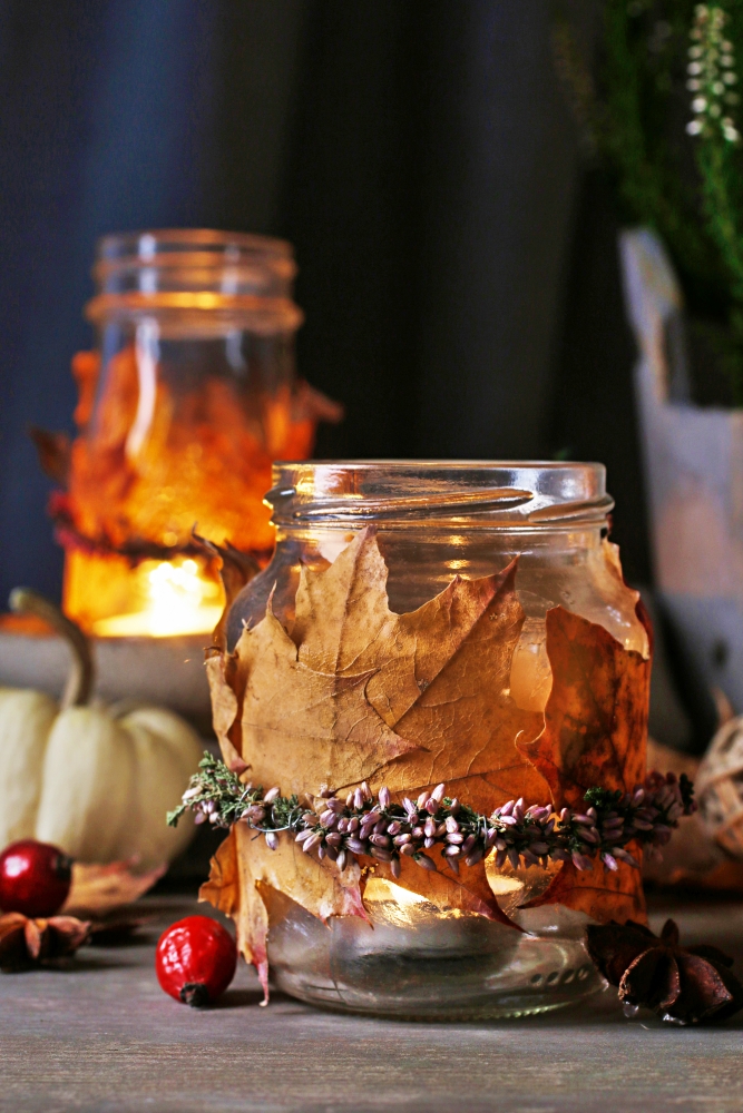 Autumn lantern jars decorated with colorful leaves and heather wreath. 