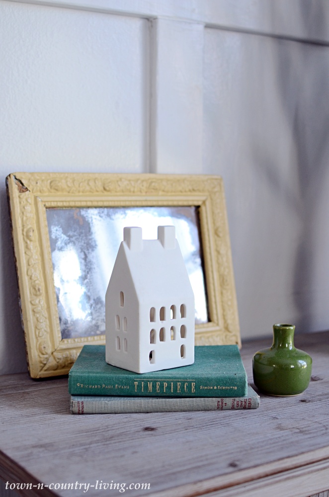 White ceramic house with a vintage mirror and books