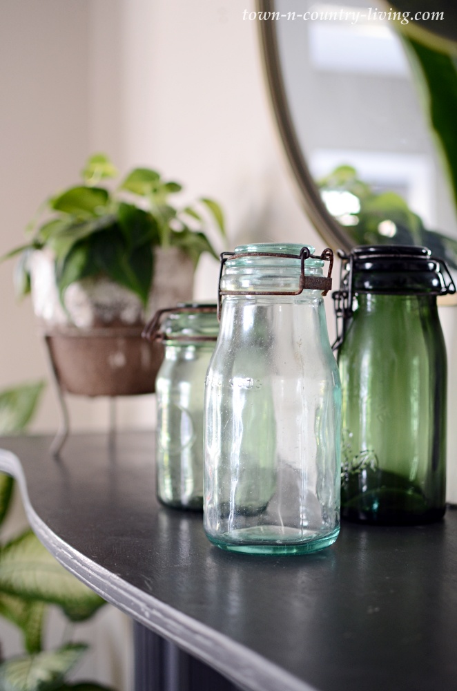 French canning jars on a black mantel with houseplants