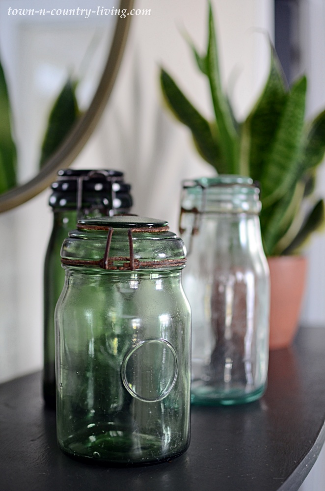 French canning jars on a black mantel with houseplants