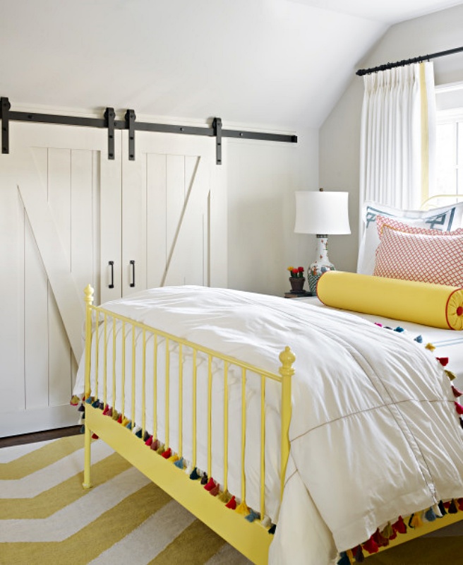 White farmhouse bedroom with yellow iron bed and tasseled comforter
