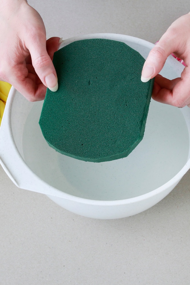 soaking a piece of florist foam in water to create a centerpiece