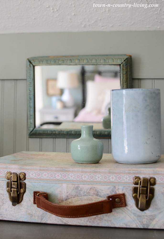 Papered decorative suitcase with pale blue vases and vintage mirror