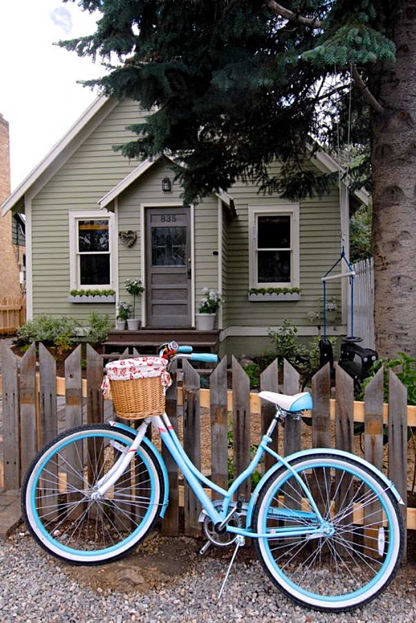 Small green cottage with picket fence and blue bike