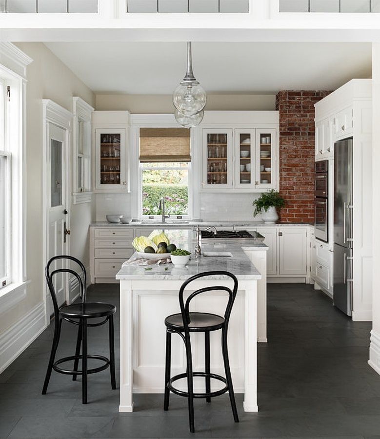 White cabinets and exposed brick wall in Tudor home kitchen