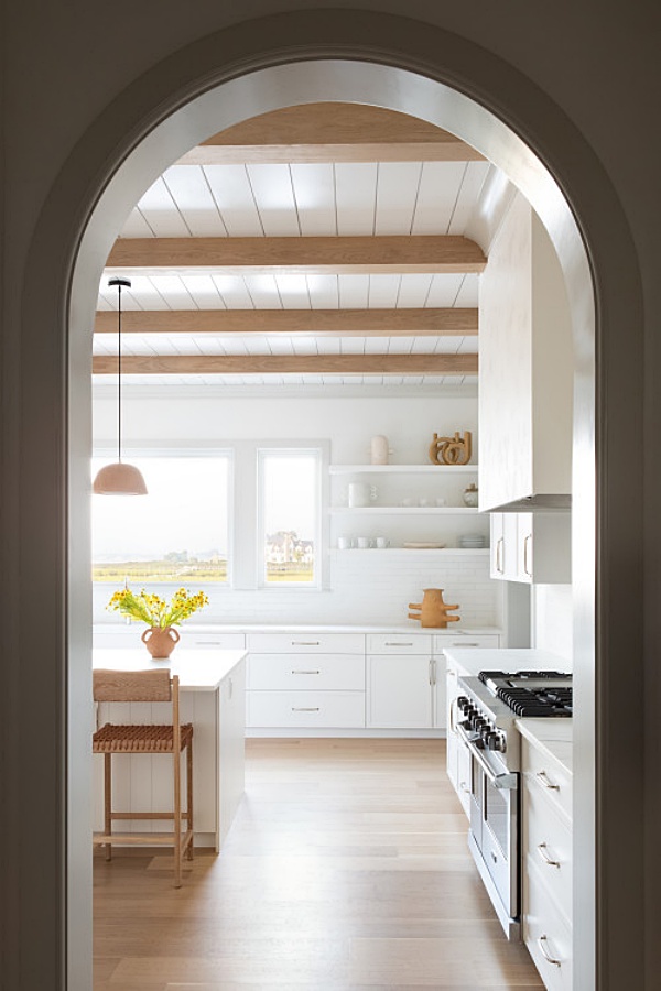 Arched door leading to wood and white kitchen