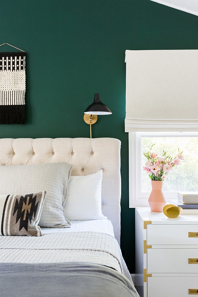 white tufted bed against dark green wall
