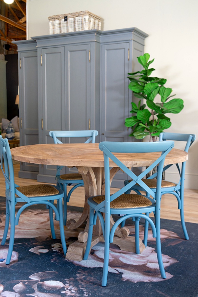 Blue cross back dining chairs around a round wood table