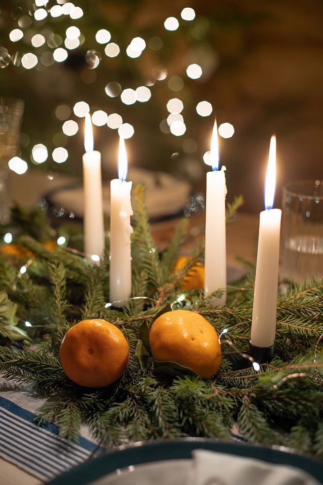 Christmas centerpiece with evergreens, candles, and oranges