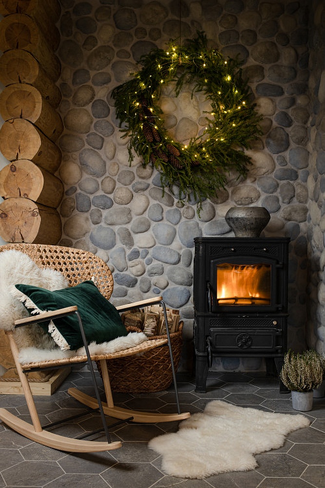 Free standing fireplace against a stone wall in a Christmas cabin
