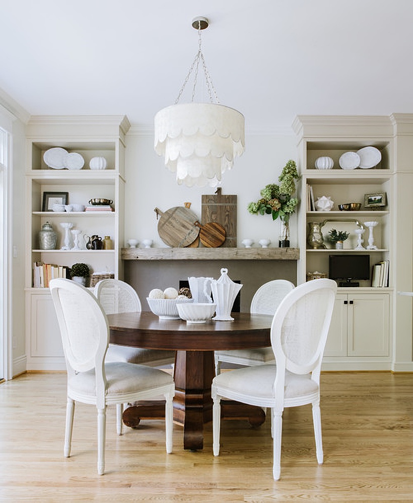 Scalloped light fixture over round, wooden dining table