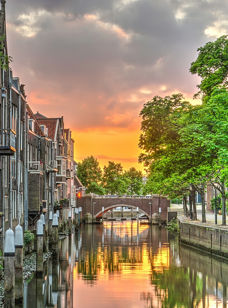Fiery sunset reflecting in a canal lined with houses in the medieval town centre of Dordrecht, the Netherlands