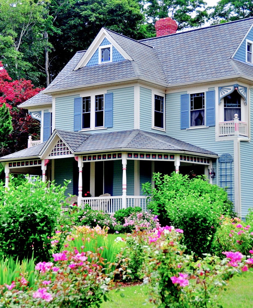  Victorian-era home with large front porch, gables, and Summer flower garden 