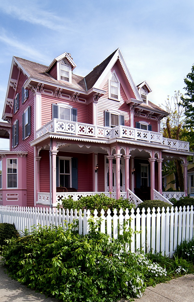 Pink Victorian house with full porch and white picket fence