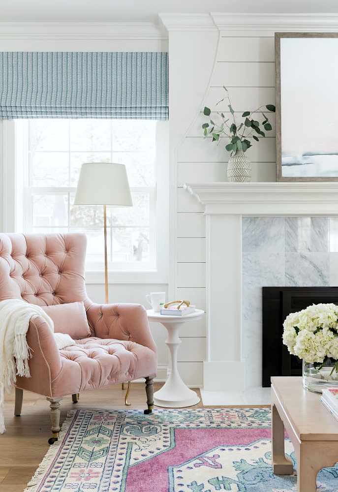 tufted pink wing chair by fireplace