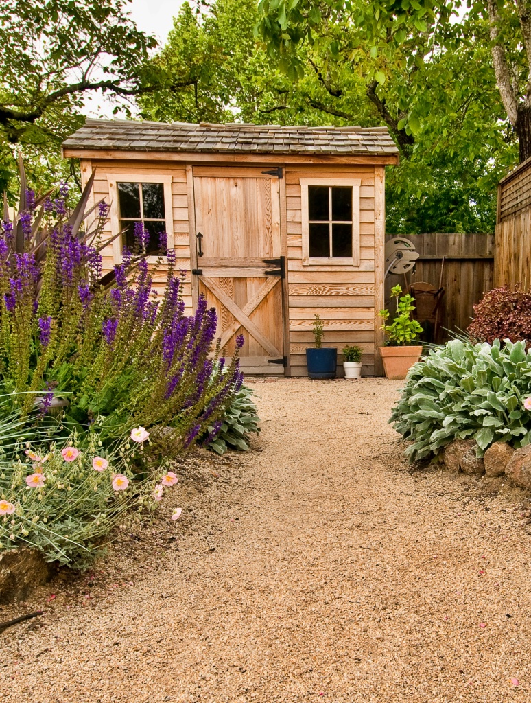 small wooden garden shed with crushed limestone path