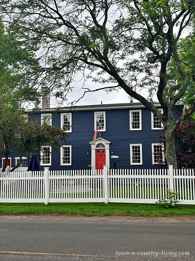 Navy blue historic home with red front door and white picket fence
