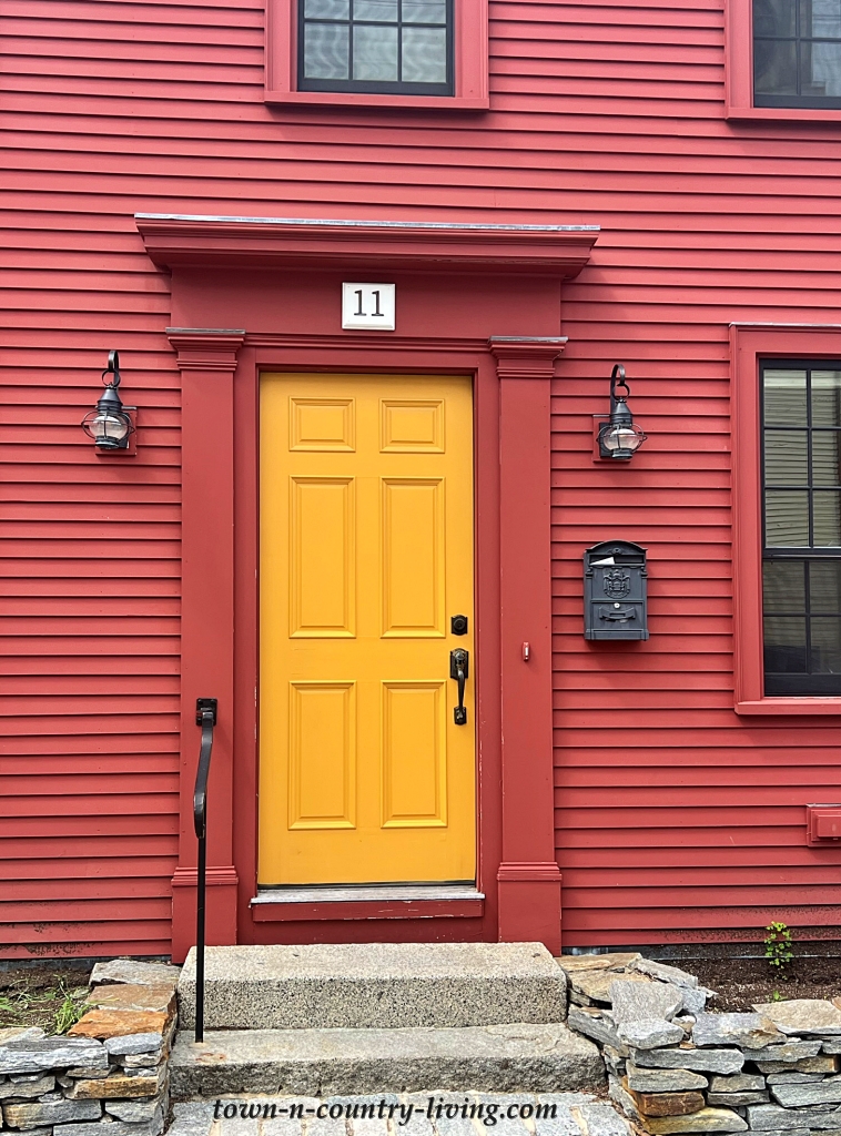 bright yellow door on deep red house in Maine