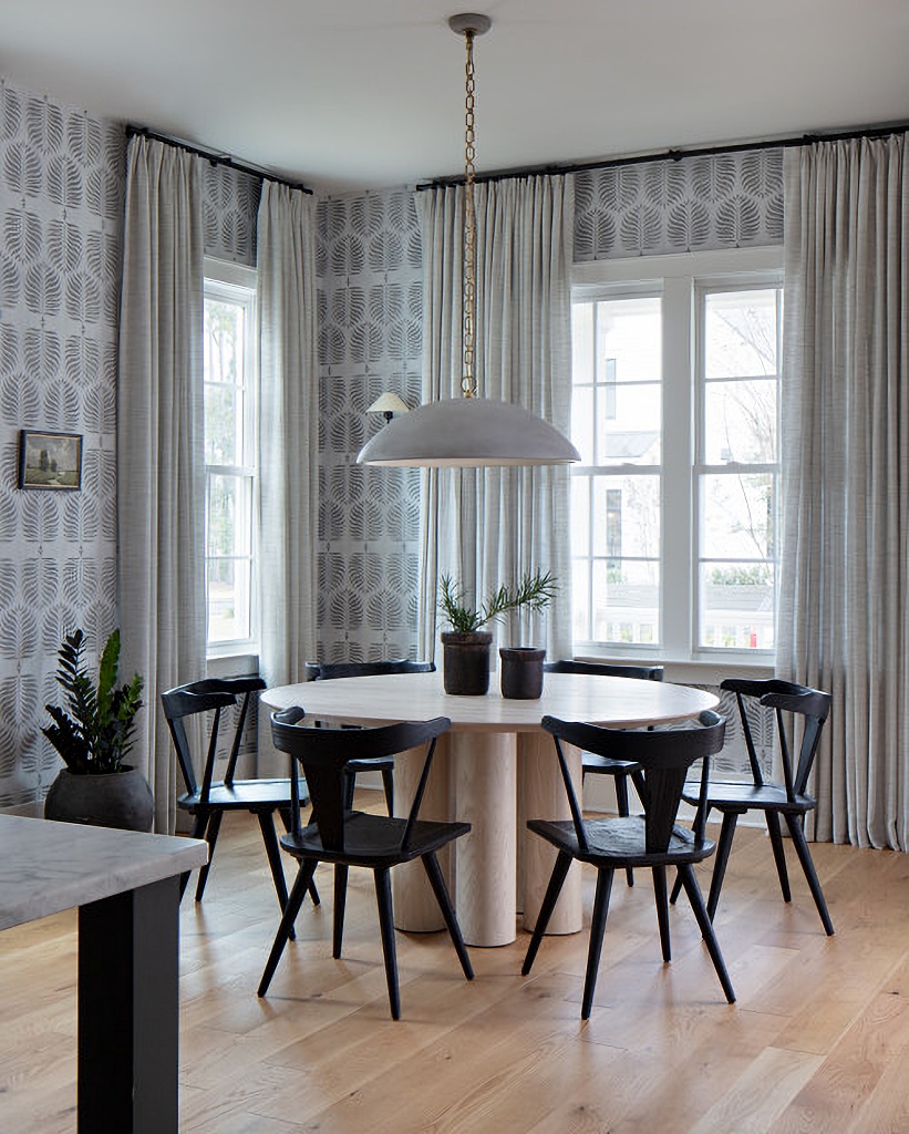 small dining room with wallpaper and black farmhouse chairs around round table