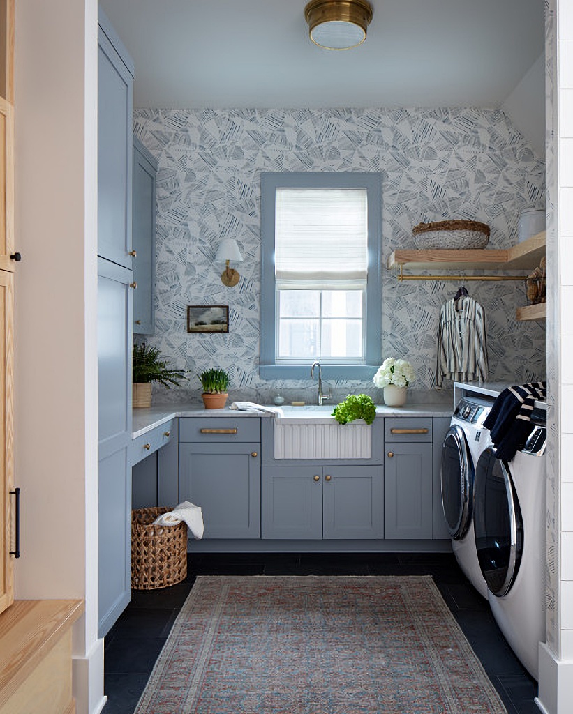 wallpapered laundry room with pale blue cabinets