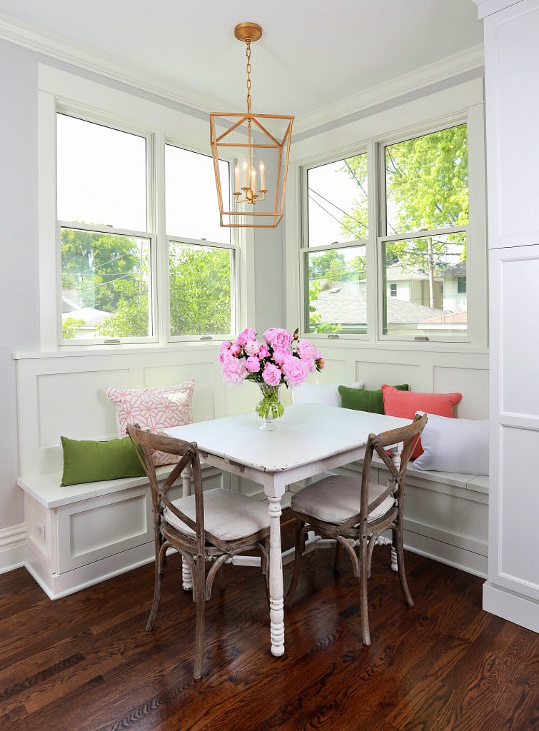 white dining nook with pink and green pillows