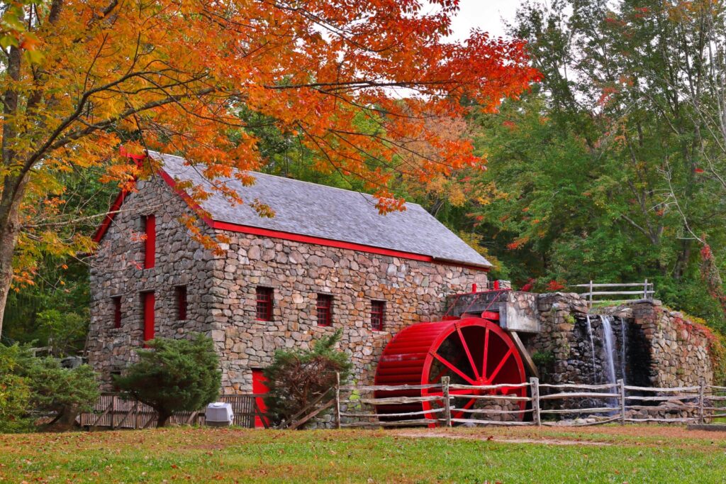 The Wayside Inn Grist Mill with water wheel and cascade water fall in Autumn.