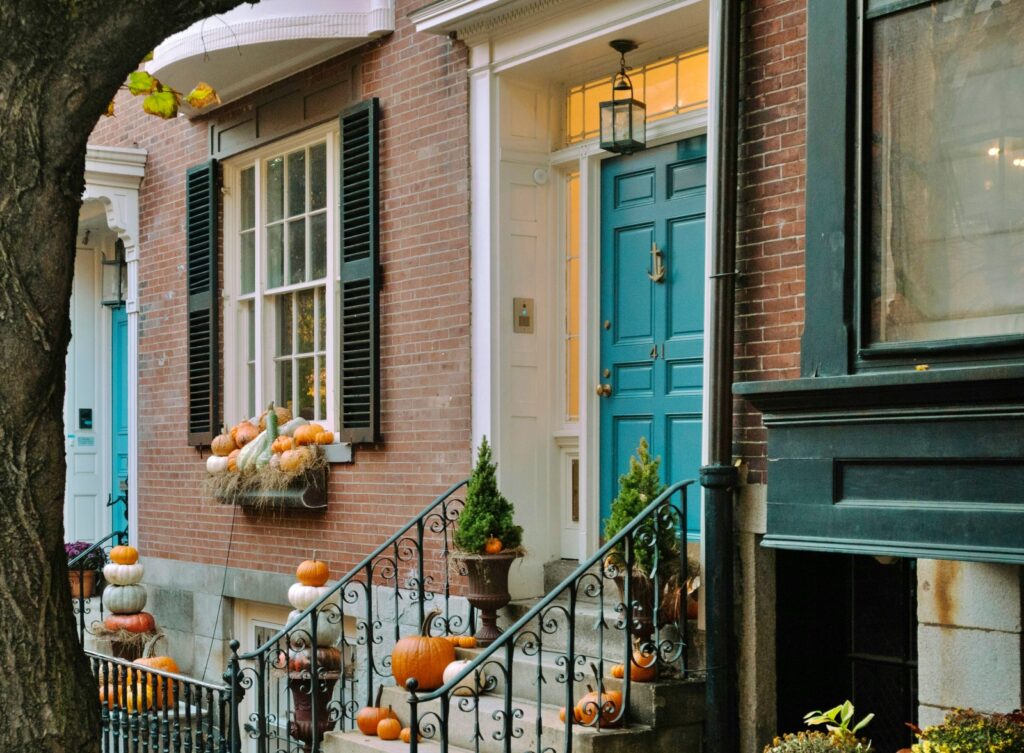 loads of pumpkins decorating the front of a brick row house