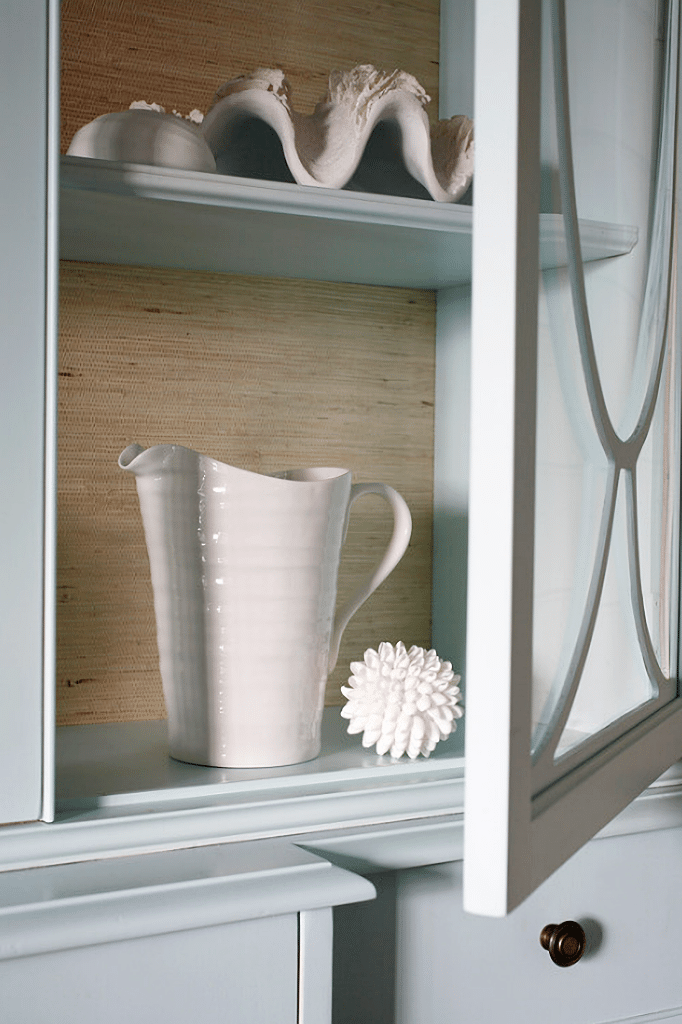 pale blue China cabinet with white dishes and seashells