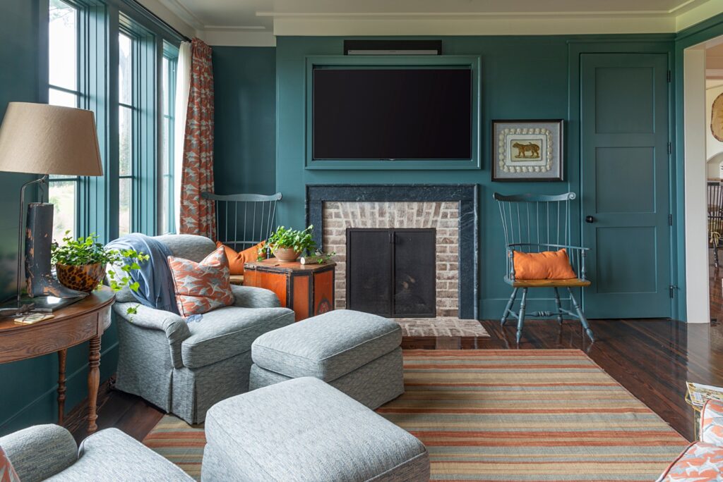 Teal walls in den with striped rug and fireplace