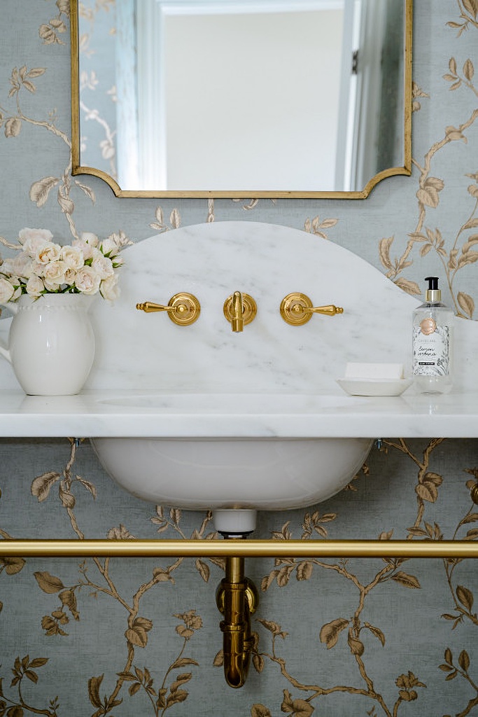 pretty powder room with wallpaper and brass accents