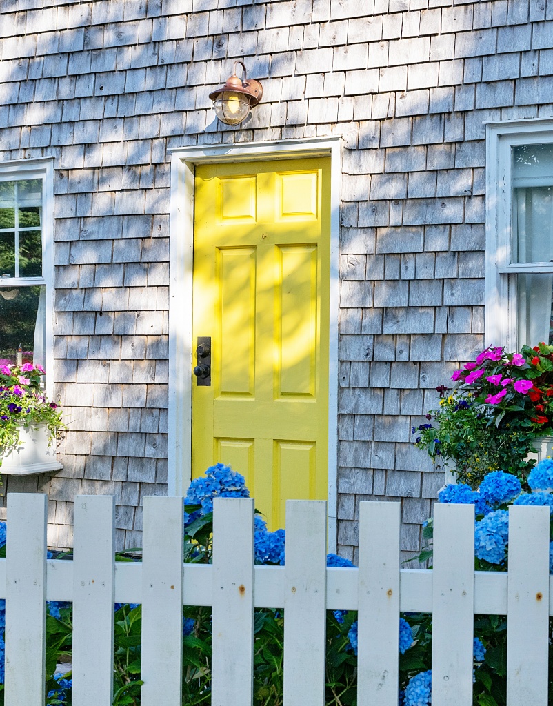 The exterior entrance to a small country cottage with grey cedar shakes