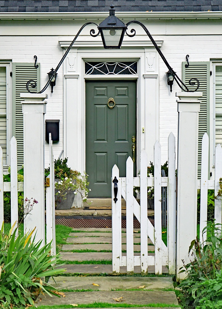 front door of small white brick house with picket fence