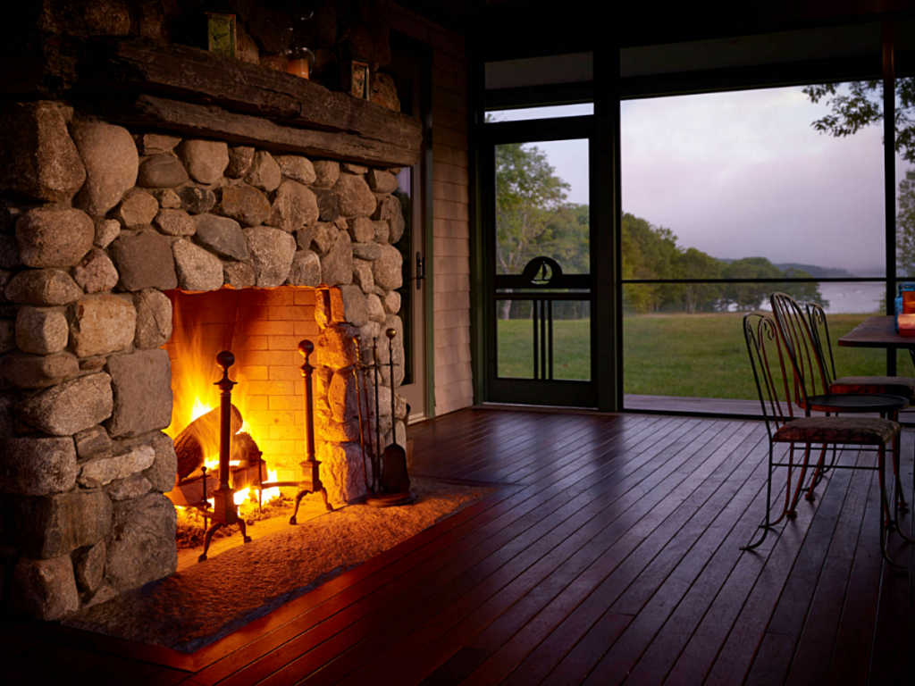 screened porch with fireplace at night