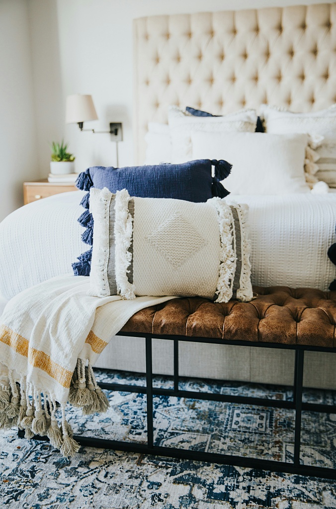 collected bedroom with tufted headboard and lots of pillows